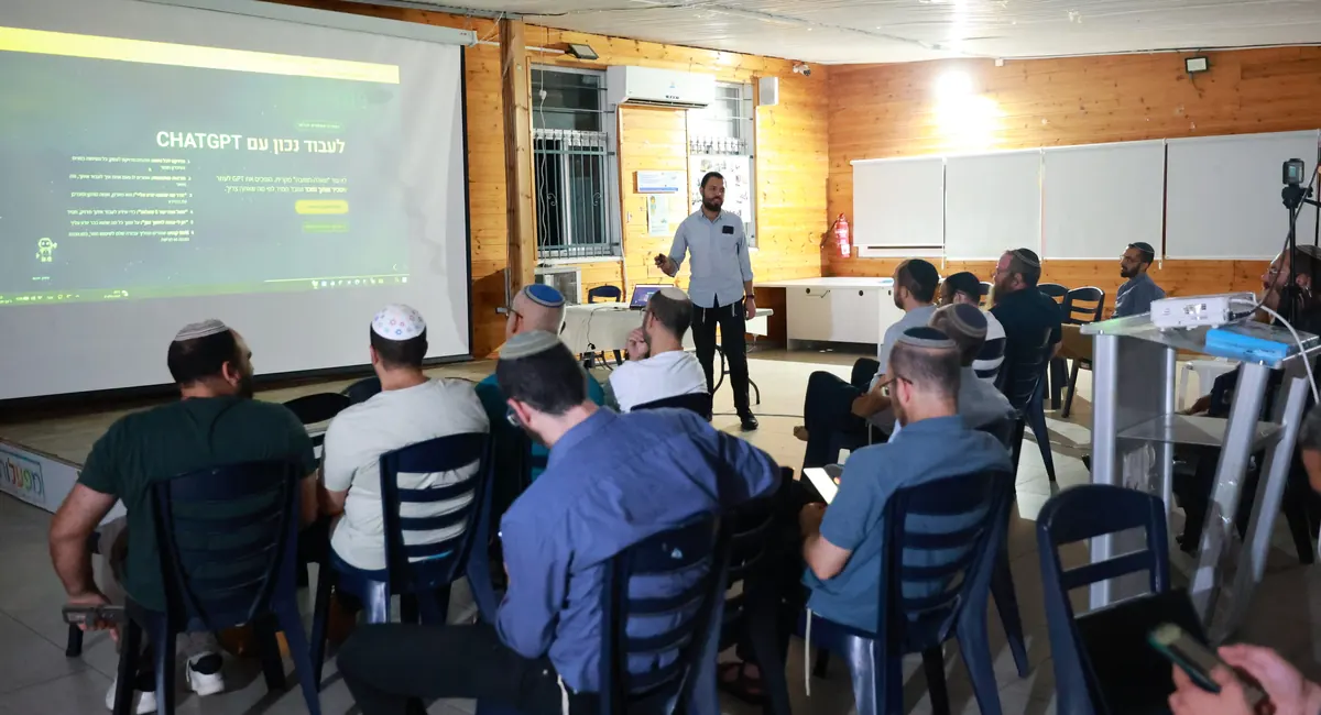 מלאכי גוטמן מציג מול קהל באולם, על המסך שקף על עבודה נכונה עם ChatGPT